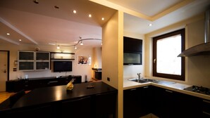 Eine moderne Küche mit dunklen Schränken, einer zentralen Kochinsel, einem eingebauten Backofen und einem Fenster für natürliches Licht.