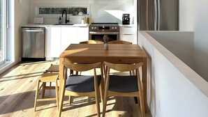 A modern kitchen with white cabinets, stainless steel appliances, and a wooden dining table with chairs.