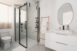 A modern bathroom with a glass-enclosed shower, a white vanity with a large mirror, and a wooden ladder for storage. - Spa and Nature at Chalet Komorebi (Sainte-Beatrix)