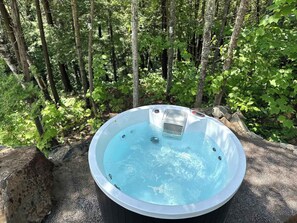 A hot tub in a forested area with a metal frame and a control panel. - Spa and Nature at Chalet Komorebi (Sainte-Beatrix)