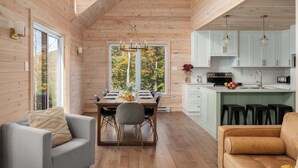 A spacious wooden cabin interior with a dining area, kitchen, and seating. - Montagnia escape, Tremblant, Private Spa & Sauna Retreat (Val-des-Lacs)