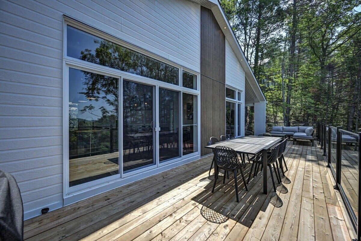 A modern house with a deck, large sliding glass doors, and a built-in seating area.