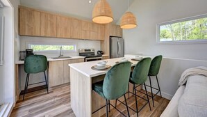 Una cocina moderna con armarios de madera, una isla central con taburetes altos e iluminación colgante.