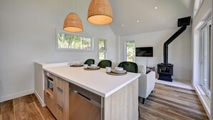 Una cocina moderna con una isla central, armarios de madera e iluminación colgante.