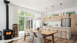 A modern kitchen with a central island, white chairs, and a large window. - Chalet w Private Thermal Spa, Nature & Relaxation (Sainte-Béatrix)