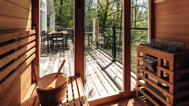 A wooden cabin interior with a sliding glass door leading to an outdoor deck. - Chalet w Private Thermal Spa, Nature & Relaxation (Sainte-Béatrix)