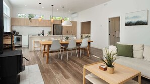 A modern kitchen with wooden cabinets, a dining area with a table and chairs, and a living room with a sofa and a coffee table. - Chalet w Private Thermal Spa, Nature & Relaxation (Sainte-Béatrix)