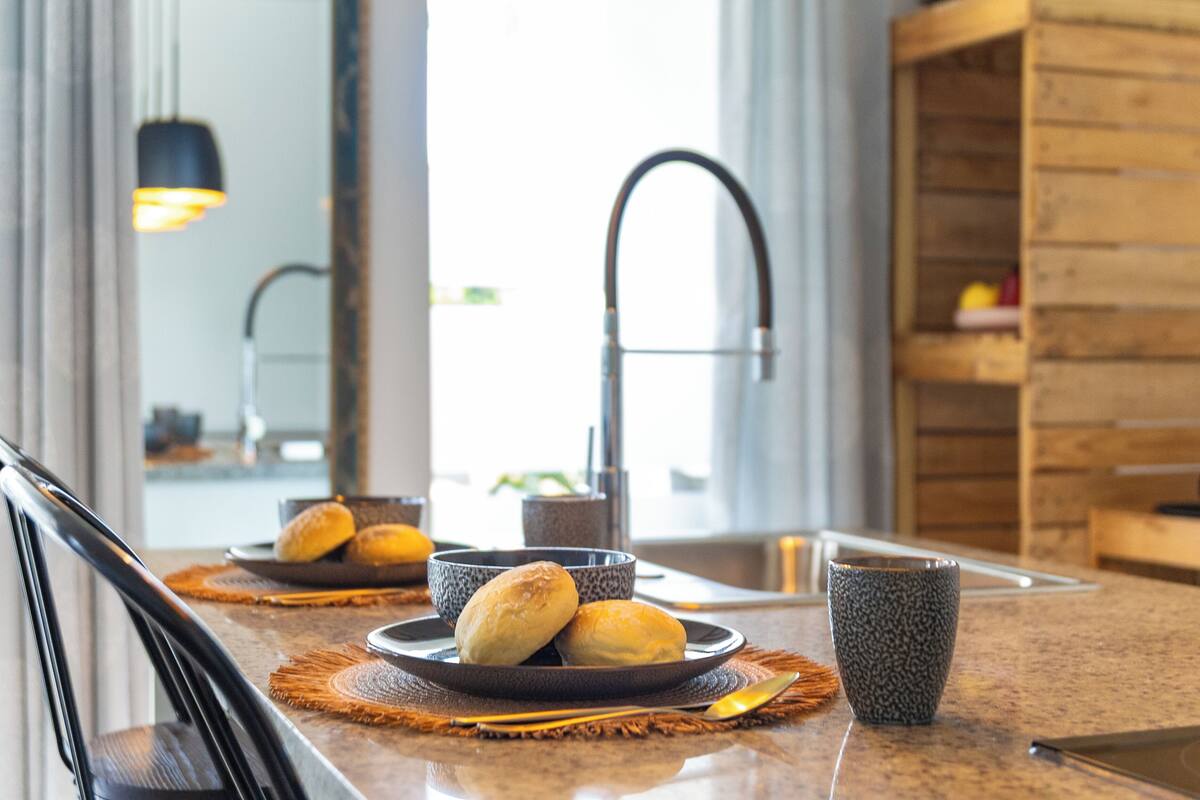 A kitchen counter with a plate of bread, a bowl, and a cup.