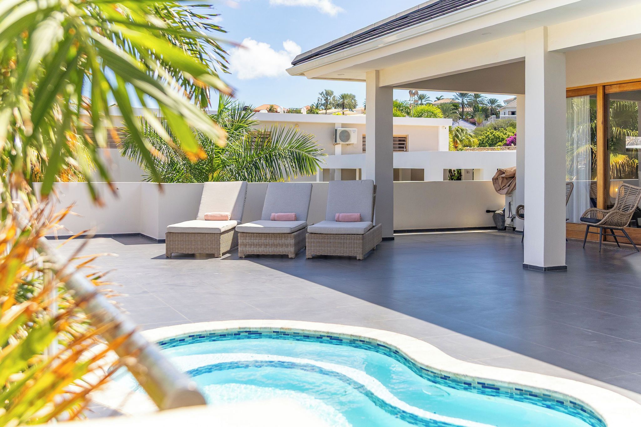 Un espace piscine avec des chaises longues et un coin salon abrité.