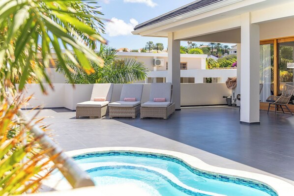 A pool area with lounge chairs and a covered seating area.
