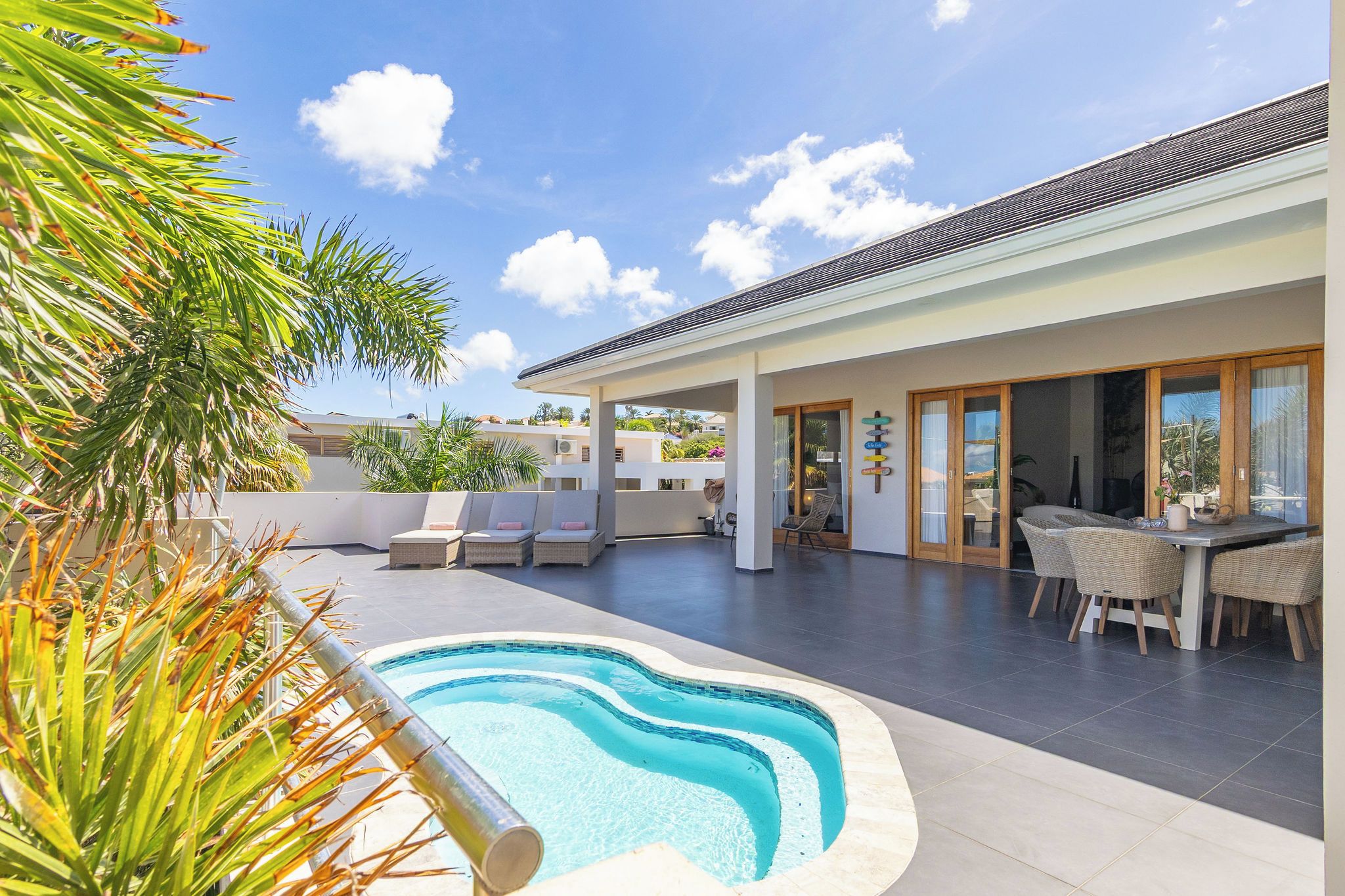 A modern outdoor pool area with lounge chairs and a dining table.