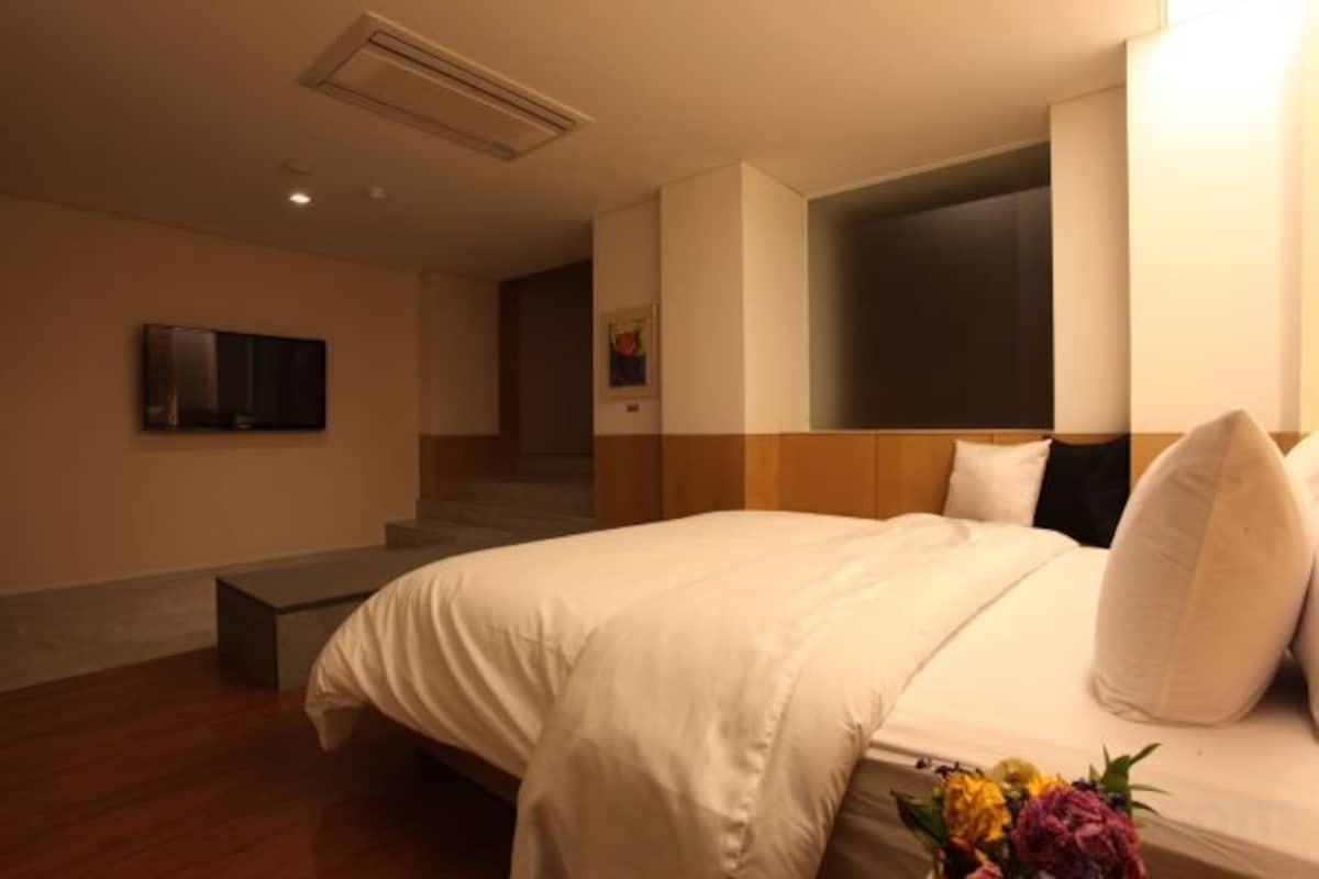 A hotel room with a bed, a flat-screen TV, and a staircase leading to another level.