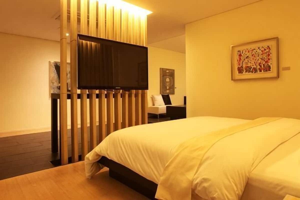 A hotel room with a bed, a television, a desk, and a chair.