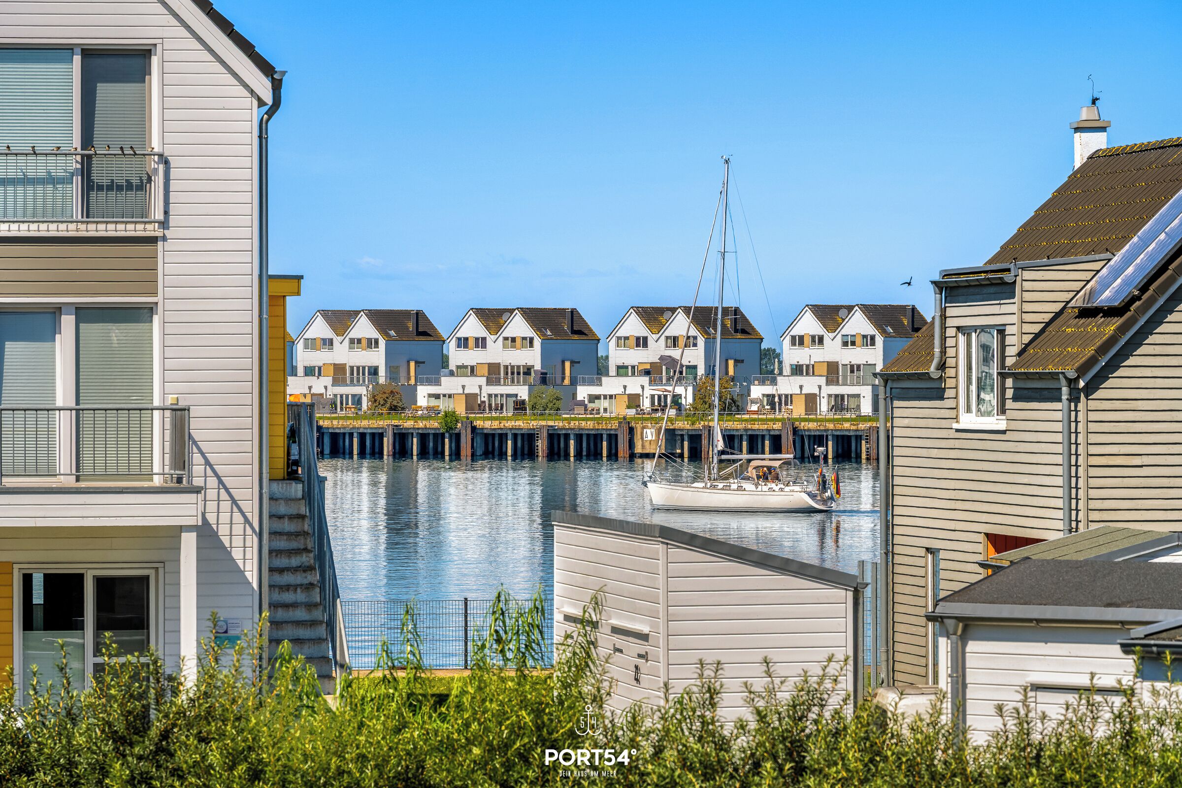 A waterfront residential area with multiple houses, a dock, and a sailboat.