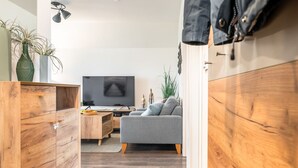 Un salon moderne avec un canapé gris, des meubles en bois, un téléviseur et une plante.