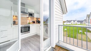 Une cuisine moderne avec des meubles blancs, un four à micro-ondes et une cuisinière.