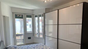 Ein Schlafzimmer mit einem Bett, einem Kleiderschrank und einem Fenster mit Blick auf Gebäude.