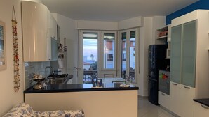 Eine moderne Küche mit einer Kochinsel, weißen Schränken und Blick auf die Stadt durch große Fenster.