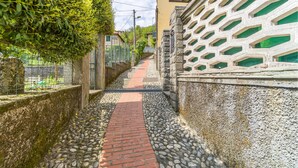 A narrow alleyway with a brick pathway, stone walls, and a green hedge. - Gorgeous apartment in Savignone with WiFi (Savignone)