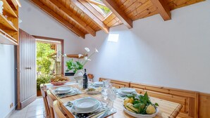 A dining area with a wooden table set for four, a vase with flowers, and a view of greenery outside. - Gorgeous apartment in Savignone with WiFi (Savignone)