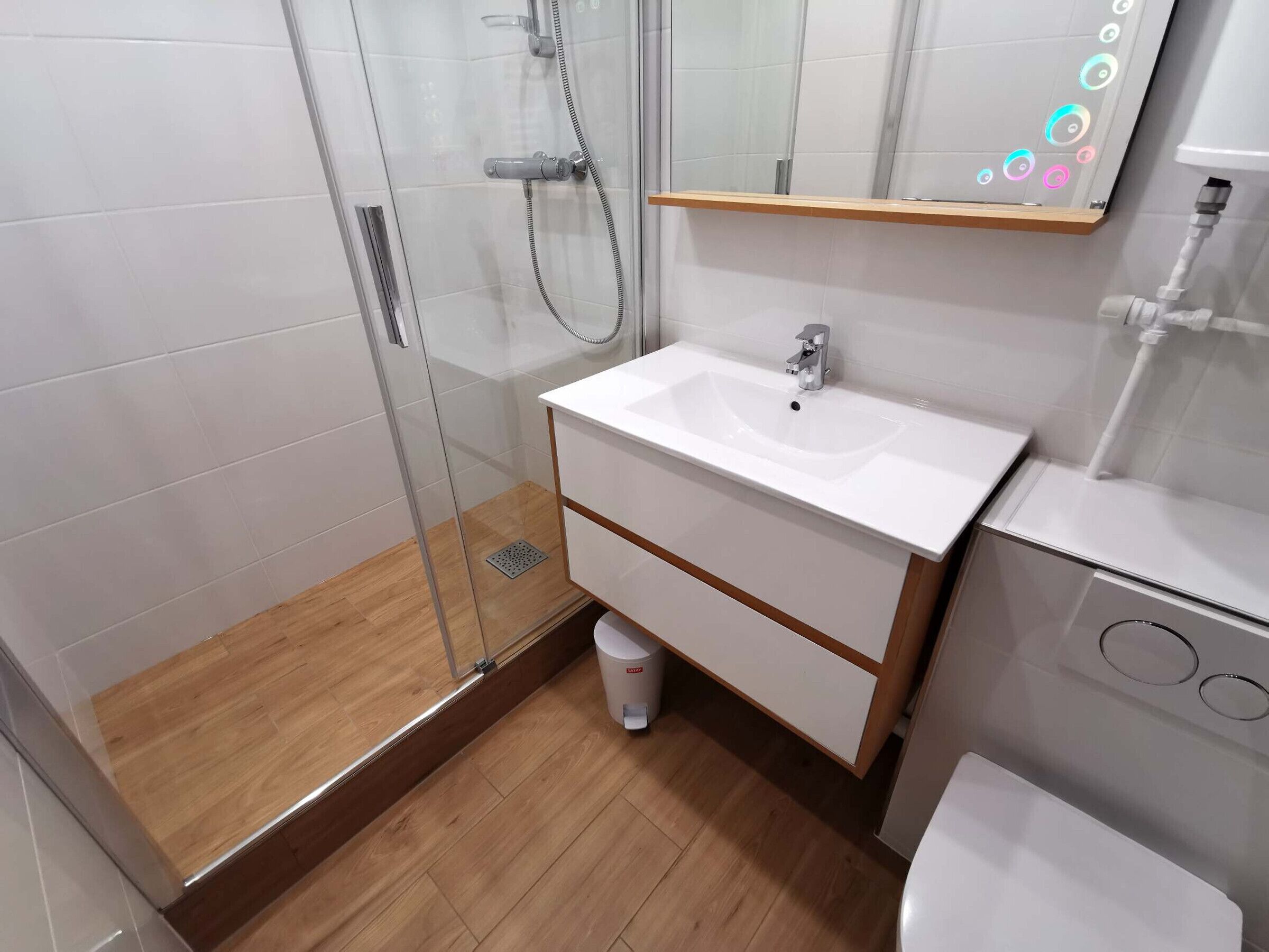 A modern bathroom with a glass shower enclosure, a white sink, and a toilet.
