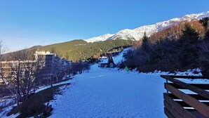 Un sentier enneigé qui mène à une région montagneuse, avec une clôture en bois sur le côté droit.