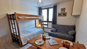 Une pièce avec un lit superposé, un canapé et une table à manger avec des assiettes, des tasses et des couverts.