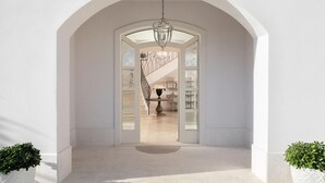 An arched doorway leading to a staircase with a chandelier, a dining table with a vase of flowers, and two potted plants. - Stunning home in Vabriga (Vabriga)