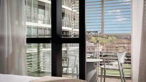 A hotel room with a large window, a bed, and a balcony with a table and chairs. - Welcome Hotel (Serravalle)