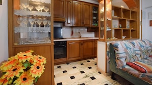Een keuken met houten kastjes, een spoelbak en een eethoek met een bank en een gestreept plaids.
