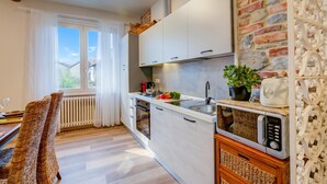 Une cuisine moderne avec des meubles blancs, un four à micro-ondes et un mur en briques.