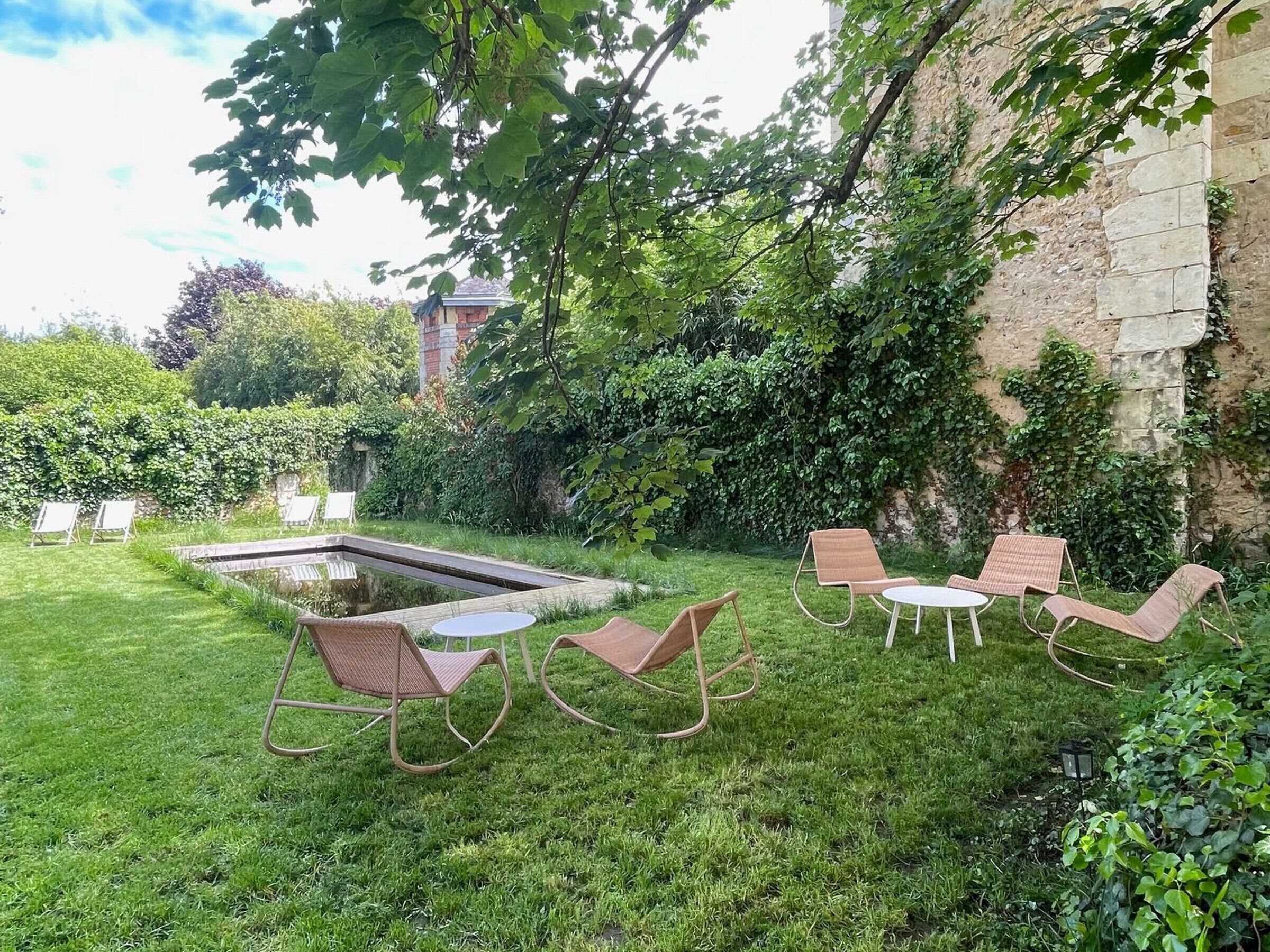 Un jardin bien entretenu, agrémenté d’un petit étang, d’un espace aménagé pour s’asseoir à l’extérieur et d’un mur en pierre.