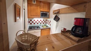 Una cocina funcional con armarios de madera, un microondas, una estufa y una cafetera.