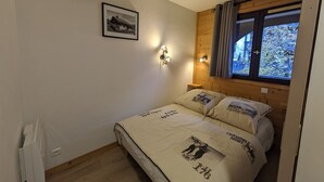 Un dormitorio con cama, un cuadro enmarcado en la pared y una ventana con cortinas.