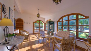 A sunlit room with wicker furniture, large windows, and a decorative lamp. - Amazing home in Siracusa (Siracusa)