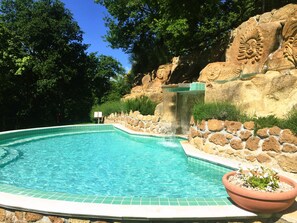 A swimming pool with a waterfall feature, surrounded by stone walls and greenery. - Residence with swimming pool in Sorano (Sorano)