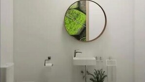 A modern bathroom with a toilet, sink, and mirror.