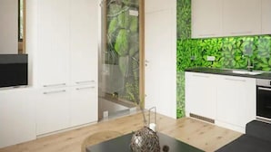 A modern kitchen with white cabinets, a green leaf-patterned backsplash, and a wooden floor.