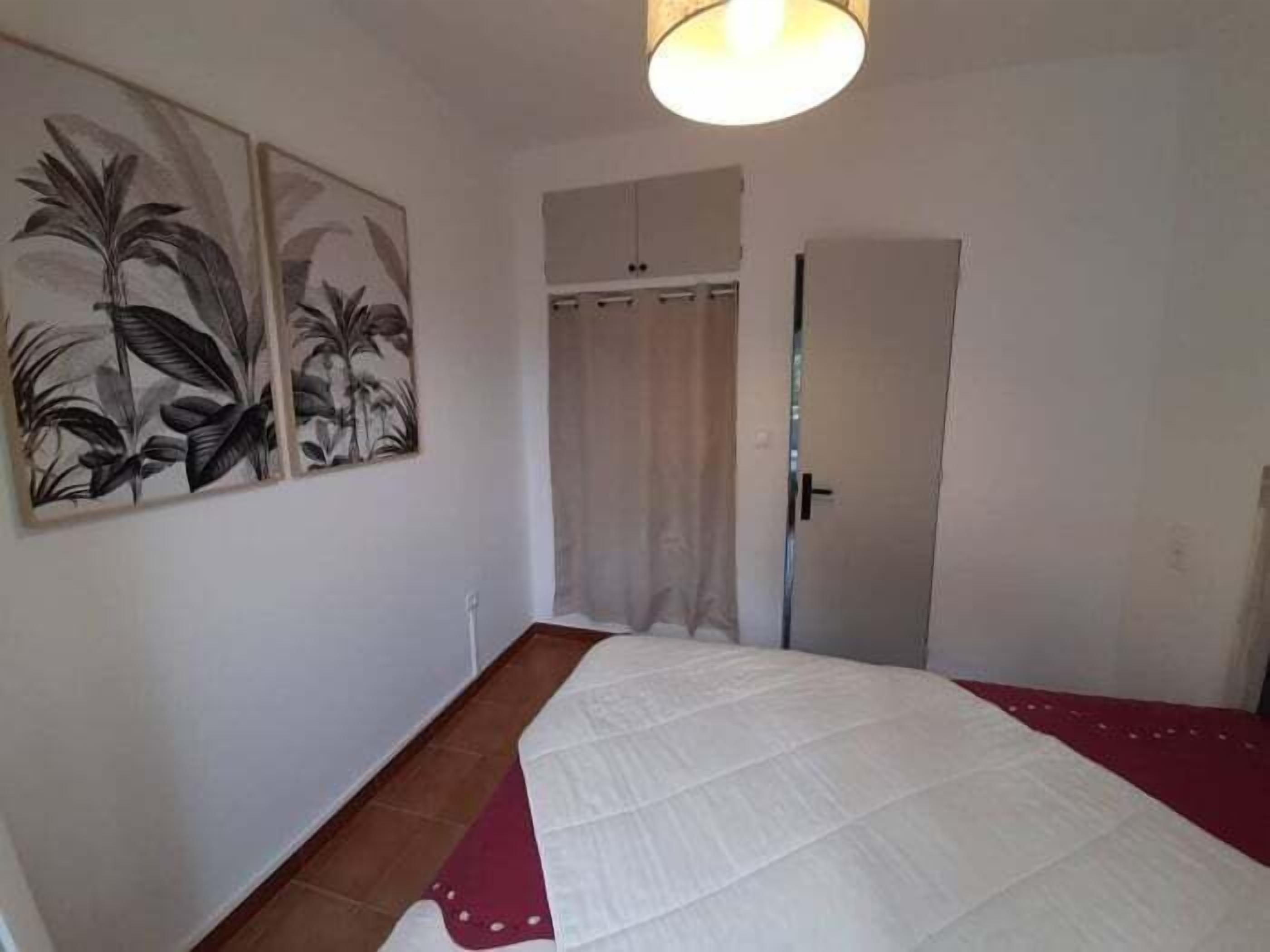 Un dormitorio con una cama, una puerta y dos cuadros en la pared.