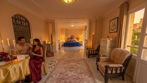 A hotel room with a bed, a sitting area with a chair, a table with candles, and a view of the outdoors. - Chez l'ami hotel (Giza)