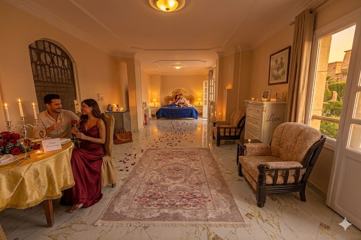 Habitación de hotel con cama, zona de estar con una silla, mesa con velas y vistas al exterior.