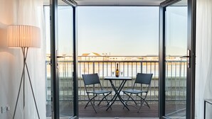 Un balcon avec une table et des chaises, une lampe et une vue sur le paysage urbain.
