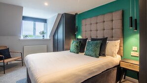 A bedroom with a large bed, a window with a view, a chair, and a radiator. - Essich Park - 2BR - Hot Tub - Sleeps 4 (Inverness)