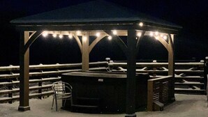 A snow-covered outdoor area with a gazebo structure, benches, and a trash can. - Essich Park - 2BR - Hot Tub - Sleeps 4 (Inverness)