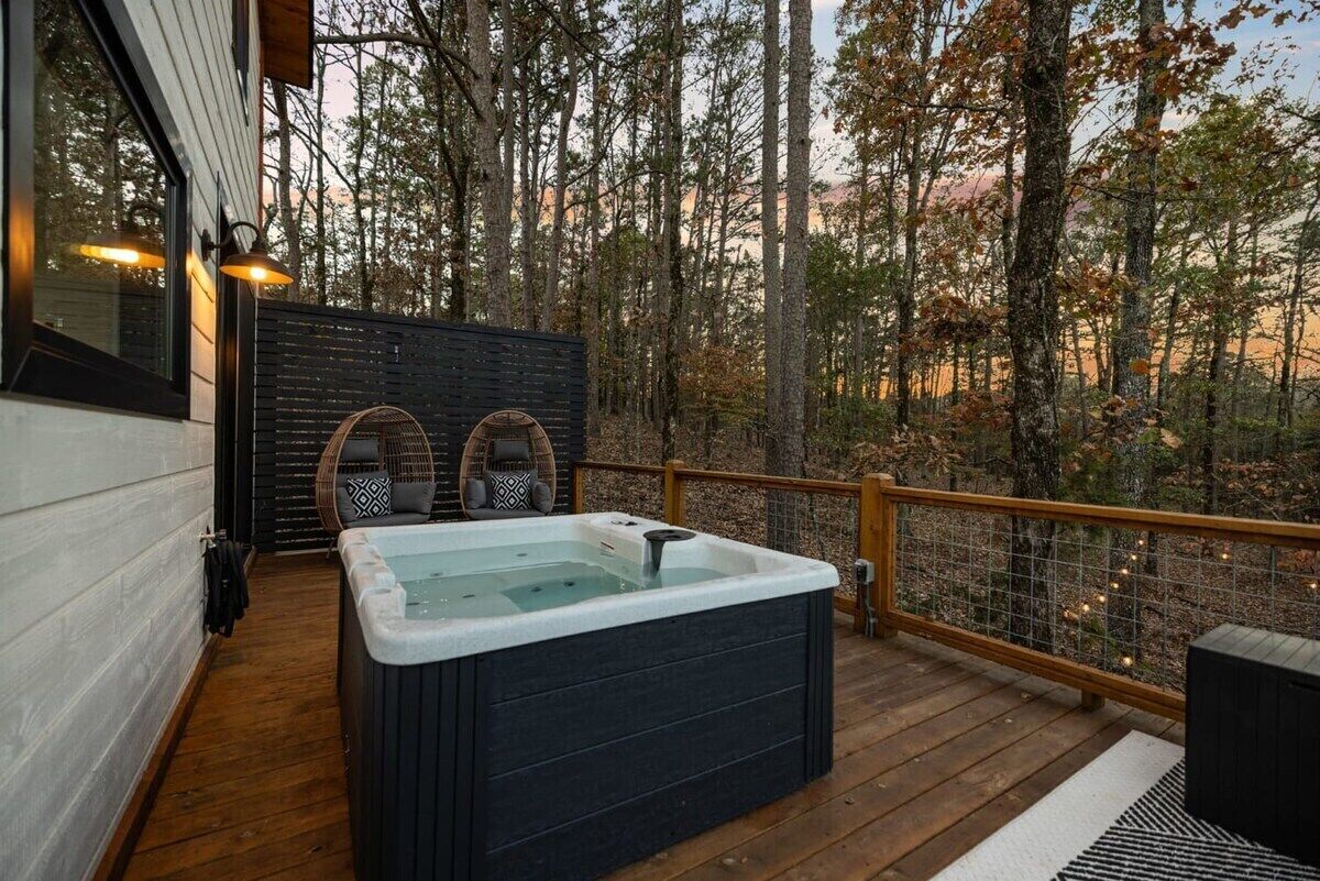 Una vasca idromassaggio su un pontile di legno con vista sugli alberi.