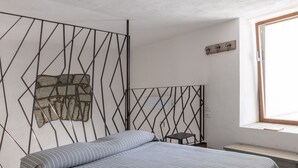 A bedroom with a bed, a window, a wall-mounted shelf, and a geometric-patterned partition. - Charming en-suite room with private terrace (Forio)