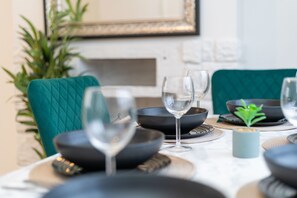 A dining table set with black bowls, wine glasses, and a small plant. - Impeccable 3-bed House in Abbeywood (London)