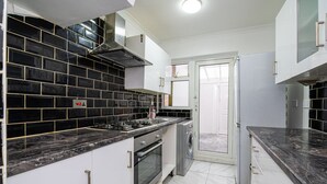Una cocina moderna con baldosas blanco y negro, electrodomésticos de acero inoxidable y muebles de cocina blancos.