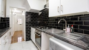 Una cocina con baldosas blanco y negro, estufa de acero inoxidable y lavadora integrada.