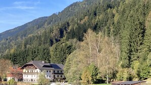 Un grand bâtiment doté d’un toit en pente, entouré d’un paysage montagneux boisé.